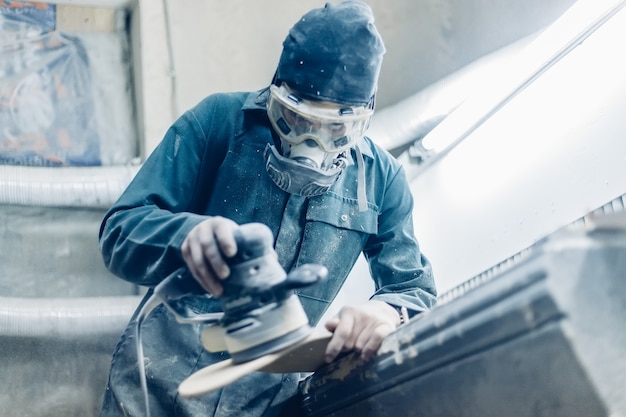 Professione, persone, falegnameria, emozione e concetto di persone: un falegname taglia una tavola con un seghetto alternativo elettrico. fabbricazione di skateboard. ha indumenti protettivi e maschera.