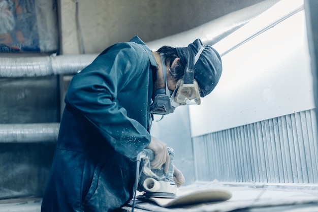 Profession, people, carpentry, emotion and people concept -A carpenter cuts a board with an electric jigsaw. manufacture of skateboards. he has protective clothing and mask.