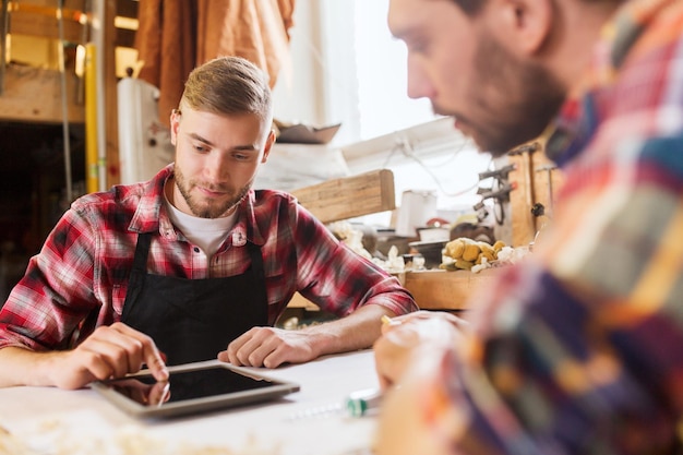 profession, technology and people concept - two workmen with tablet pc computer and blueprint at workshop