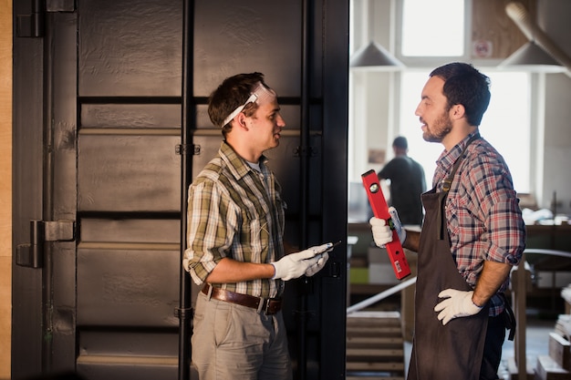 Profession, technology and people concept - two workmen with tablet pc computer at workshop