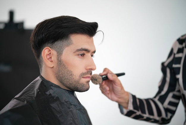 Professional actor preparation before shoot Handsome young man applying by professional make up of visagist Male makeup