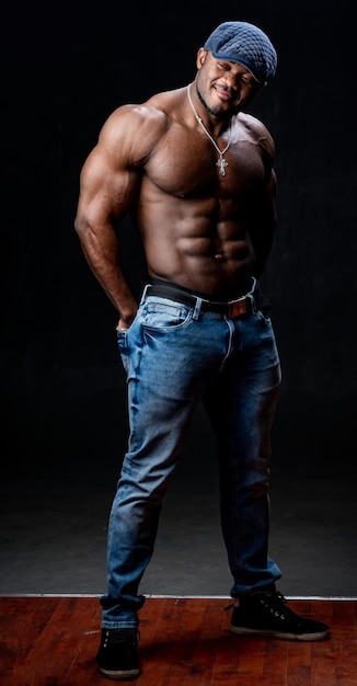 Professional african american sportsman posing on camera in casual clothes. Black studio background. Hands in pockets.