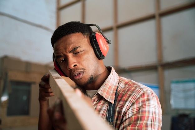 Professional african carpenter taking measurements and looking at wood