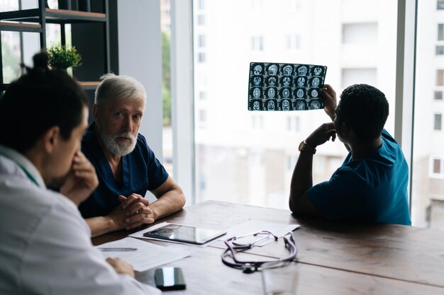 Medico africano professionista che indossa un vestito medico chirurgo blu che fa rapporto ai colleghi