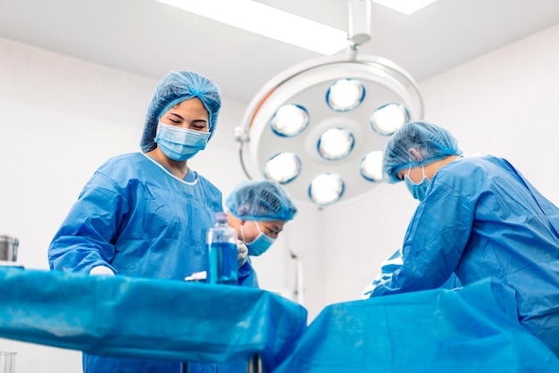 写真 専門の麻酔科医の医師の医療チームと現代の病院手術緊急治療室で手術器具を使って手術を行う婦人科手術の患者を準備するアシスタント