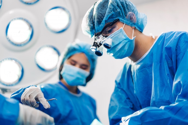 Professional anesthesiologist doctor medical team and assistant preparing patient to gynecological surgery performing operating with surgery equipment in modern hospital operation emergency room