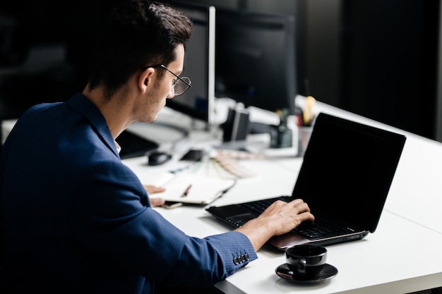 Professional architect dressed in a business suit works on the laptop in the office .