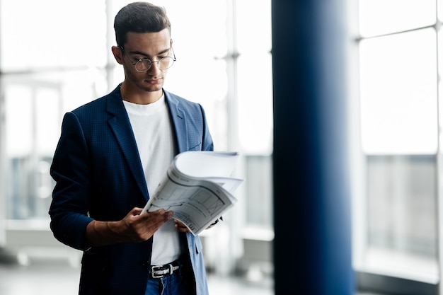 Professional architect in stylish clothes holds sheet with drawing in his hands in the hall of modern building .