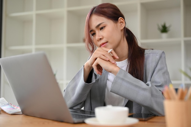 Professional asian businesswoman focusing on her work looking at laptop screen