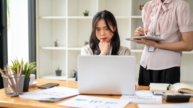 Professional Asian businesswoman is looking at her laptop screen with a serious and thoughtful face