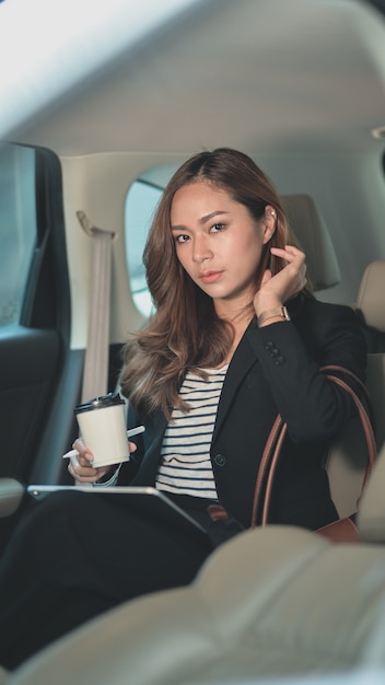 Professional asian businesswoman looking while sitting on the back seat of the car 