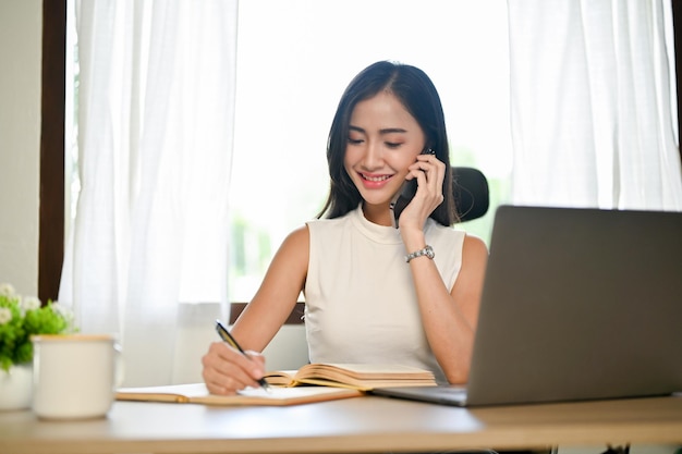 사무실에서 일하는 동안 전화 통화를 하는 전문 아시아 여성