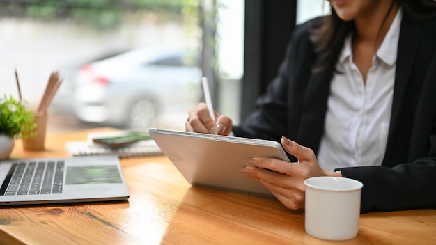 Professional Asian businesswoman using tablet to manage her work schedule cropped