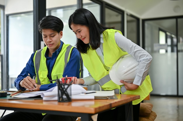 A professional Asian female construction engineer is planning a building process with her colleague