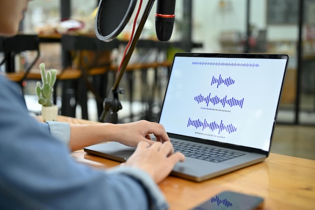 A professional Asian male radio producer adjusting the record sounds on his laptop