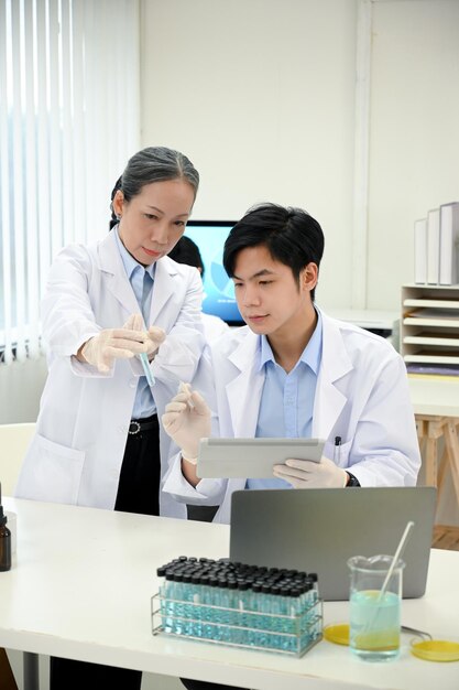 Professional asian middleaged female scientist training and\
giving a medical advice to her coworker