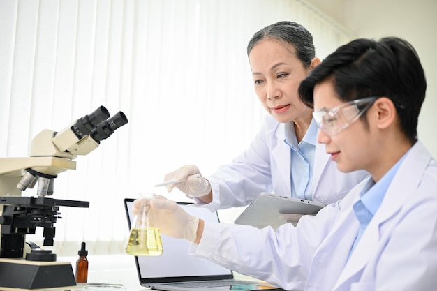 Professional Asian middleaged female scientist training a young male scientist in the lab