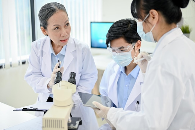 Профессиональная азиатская старшая женщина-медицинский специалист обучает двух молодых младших медицинских специалистов