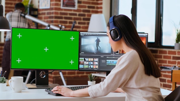 Professional asian woman working on a media project next to green screen