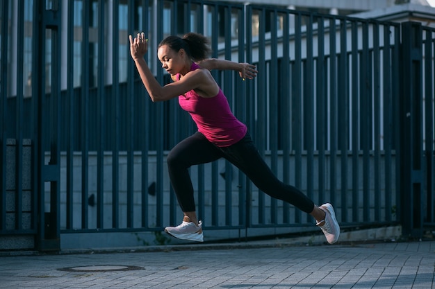 Professional athlete in the street running quickly in sporty clothes