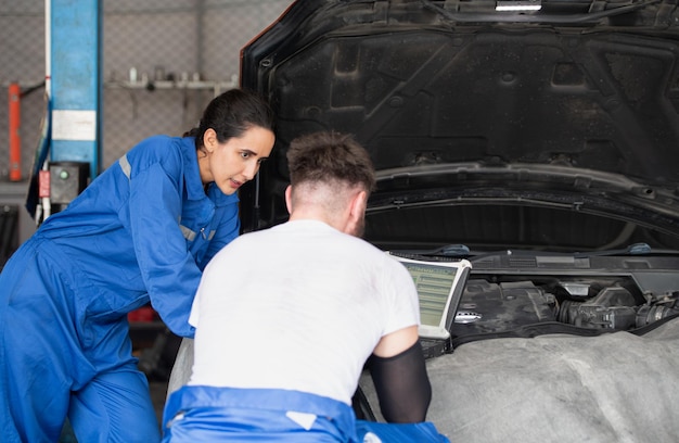 Professional auto mechanic man and woman working together in auto repair shop