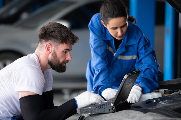 Professional auto mechanic man and woman working together in auto repair shop