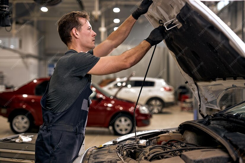 Premium Photo Professional auto mechanic working under car hood in repair garage closing or