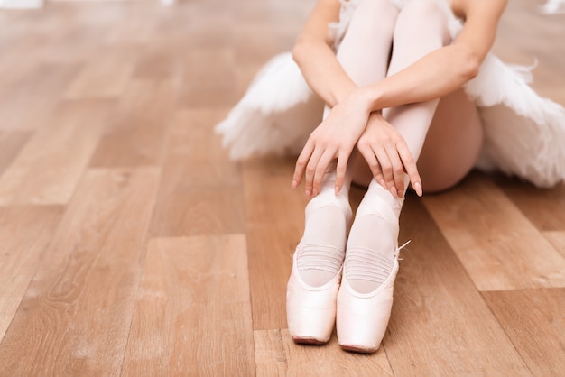 Una ballerina professionista è seduta sul pavimento.