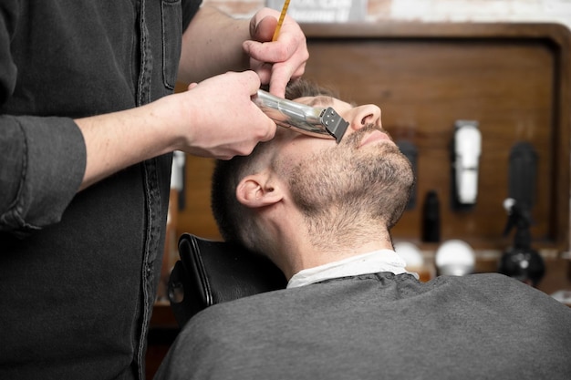 Photo professional barber cutting beard of handsome man high quality photography