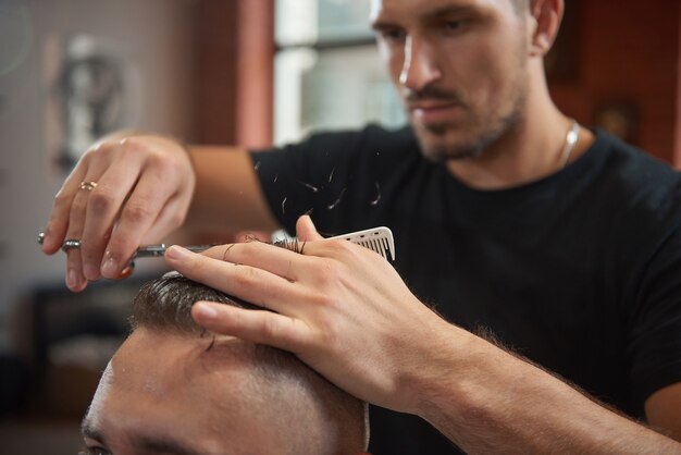 Barbiere professionista che dà al suo cliente un taglio di capelli.