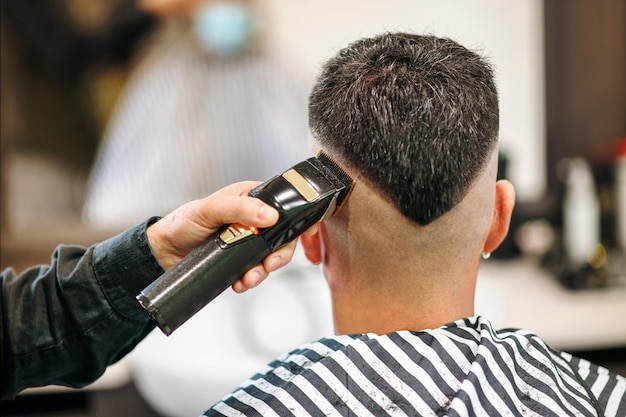 Premium Photo | Professional barber using an electric shaver or trimmer to neaten the modern v-shaped hairstyle of a male customer viewed from the rear in close up in a barbershop Premium Photo | Professional barber using an electric shaver or trimmer to neaten the modern v-shaped hairstyle of a male customer viewed from the rear in close up in a barbershop