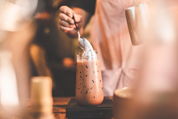 Professional barista making beverage chocolate drink from dark cocoa powder in brown mug with hot milk having sweet aroma in cup at vintage cafe background in the morning breakfast