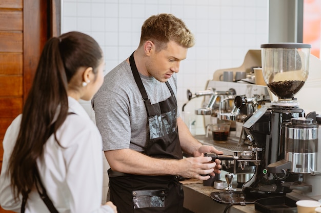 Photo professional barista working in the cafe teaching make a coffee with espresso machine to new young staff