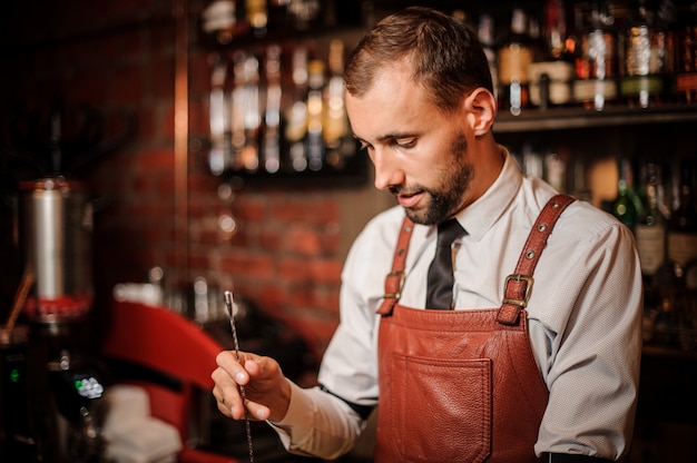 Professional bartender stirring a cocktail with spoon