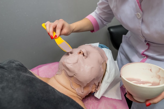 A professional beautician apply an alginate mask on the client's face