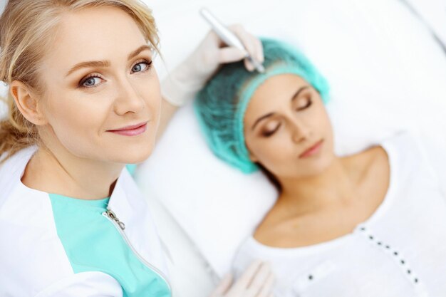 Photo professional beautician doing eyebrow tattoo at woman face. permanent brow makeup in beauty salon, closeup. cosmetology treatment.