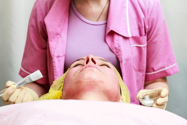 Professional - beautician puts on the skin for the chemical peeling agent with a brush, close-up.