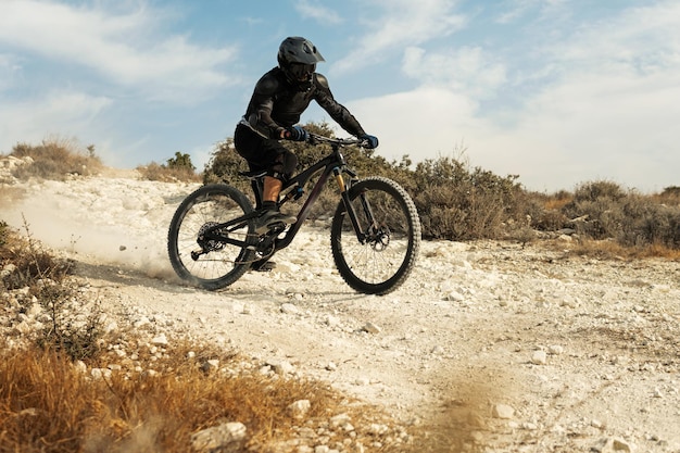 Professional bike rider fully equipped with protective gear during downhill ride on his bicycle