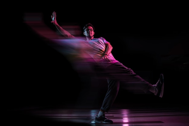 Professional break dancer jumping practicing modern hiphop dance in pink neon light blur effect