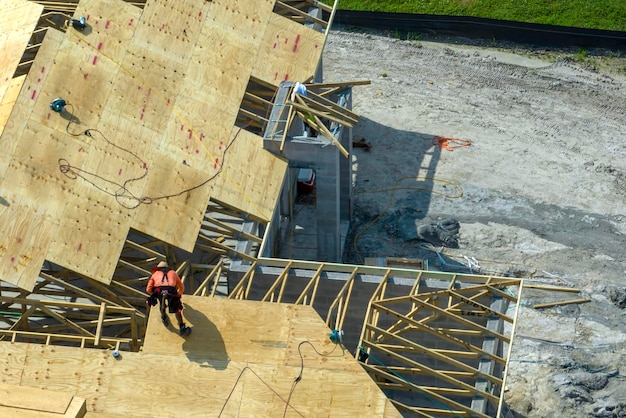 Professional builders working on roof construction of unfinished suburban home with wooden frame structure in Florida rural area Concept of housing development in America