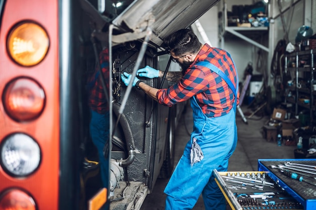 Foto meccanico di autobus professionista che lavora nel servizio di riparazione di veicoli.