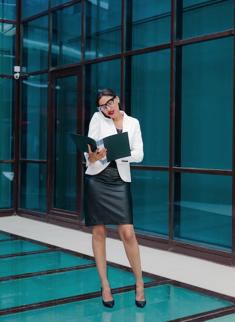 Professional business afro woman in elegant white jacket and skirt with folder with documents in her hands