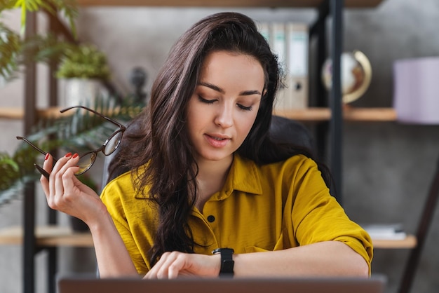 Профессиональная бизнес-женщина проверяет время и видит наручные часы в домашнем офисе