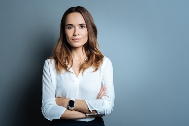 Professional businesswoman. Confident beautiful optimistic businesswoman standing cross armed and looking at you while being ready to work