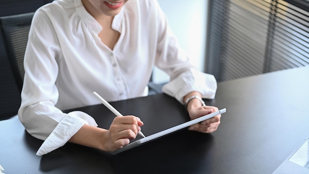 Professional businesswoman using digital tablet and preparing annual financial report at office desk