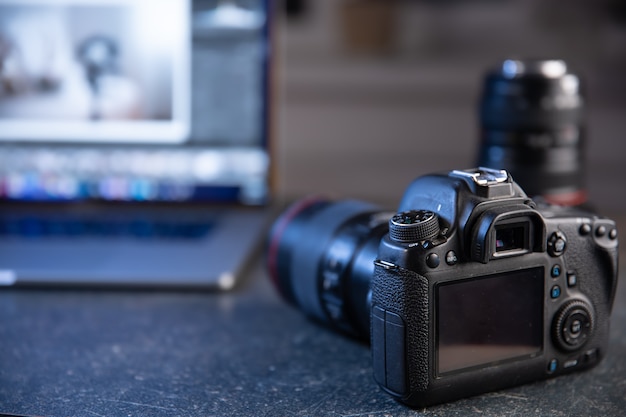 Professional camera on a blurred background with a laptop. The concept of working with photos and videos.