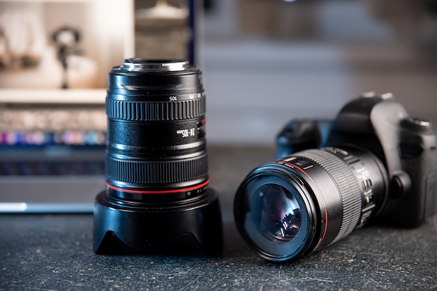 Professional camera and lens close-up on a photographer's desktop on a blurred background.