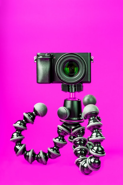 Фото Профессиональная камера на штатив, на розовом фоне. запишите видео и фото для своего блога или отчета.