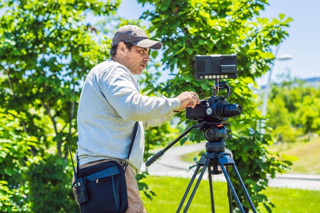 Un cameraman professionista prepara una macchina fotografica e un treppiede prima delle riprese.