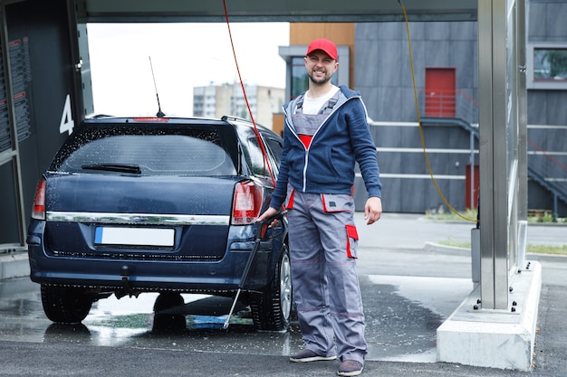 Professional car wash worker is washing client's car